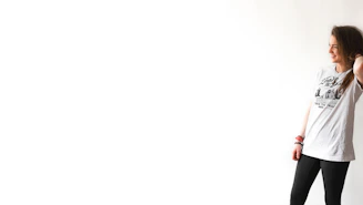 Side profile of a person wearing a minimalist graphic tee and relaxed fit pants in soft natural light