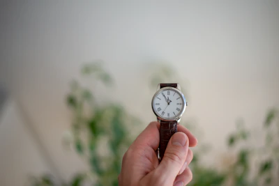 A hand holding a premium watch with a slow-living inspired design.