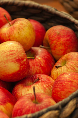 A vibrant basket overflowing with ripe, colorful apples glistening in natural light.