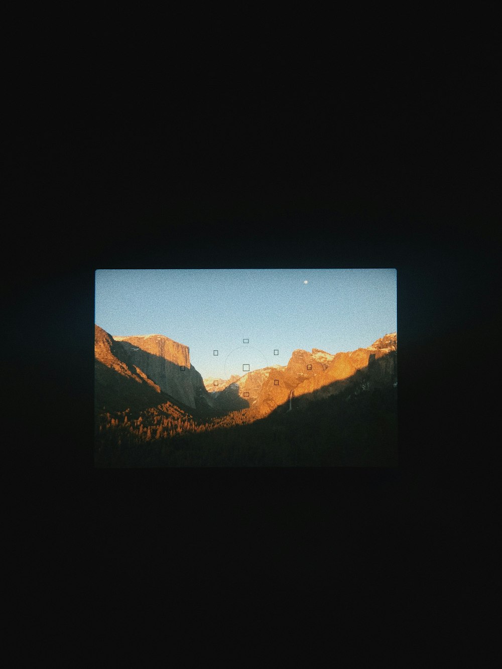 a view of a mountain range with a moon in the sky