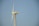 A tall wind turbine with three blades is set against a clear blue sky. The equipment is labeled with 'Solon 1250' on the nacelle, which is mounted on a lattice-style tower.