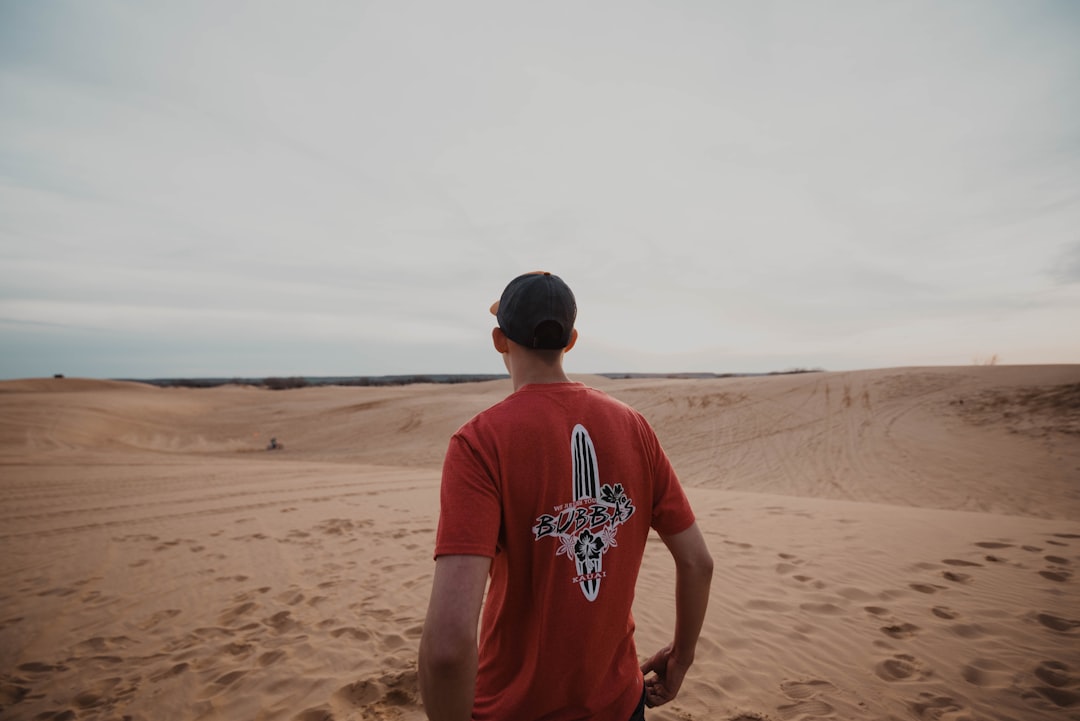 man in orange t-shirt on desert at daytime