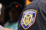 A close-up view of a patch on a uniform, reading 'Taxi and Limousine Commission City of New York' with a yellow and blue emblem showing various figures and symbols.