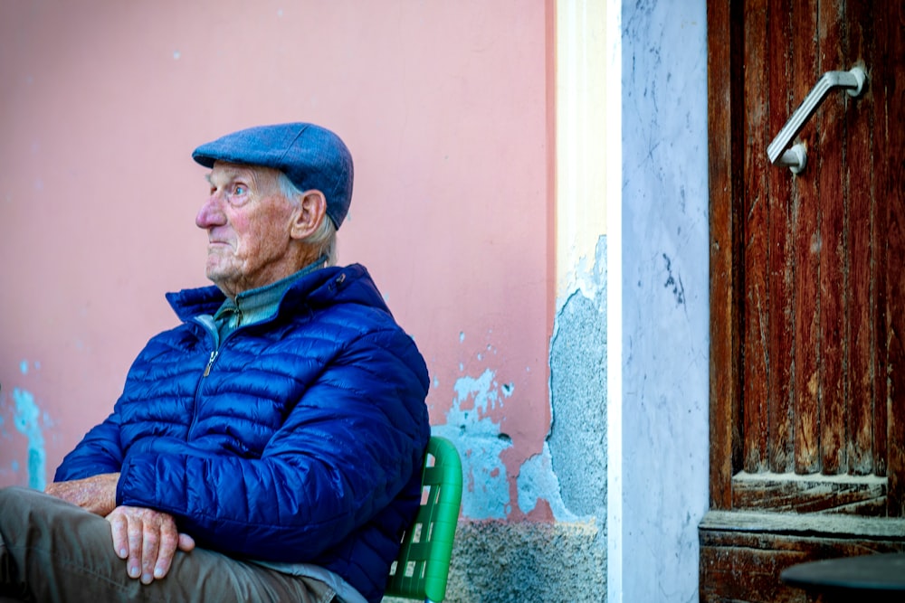 man wearing blue bubble jacket while sitting on chair