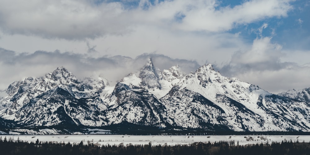 snow covered mountain and valley under white cloudy sky