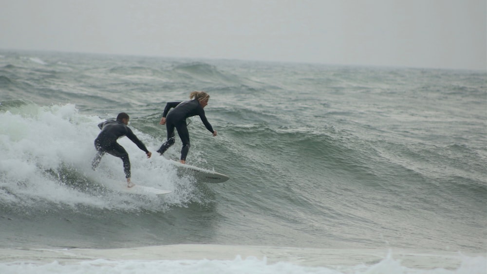 two person surfing during daytime