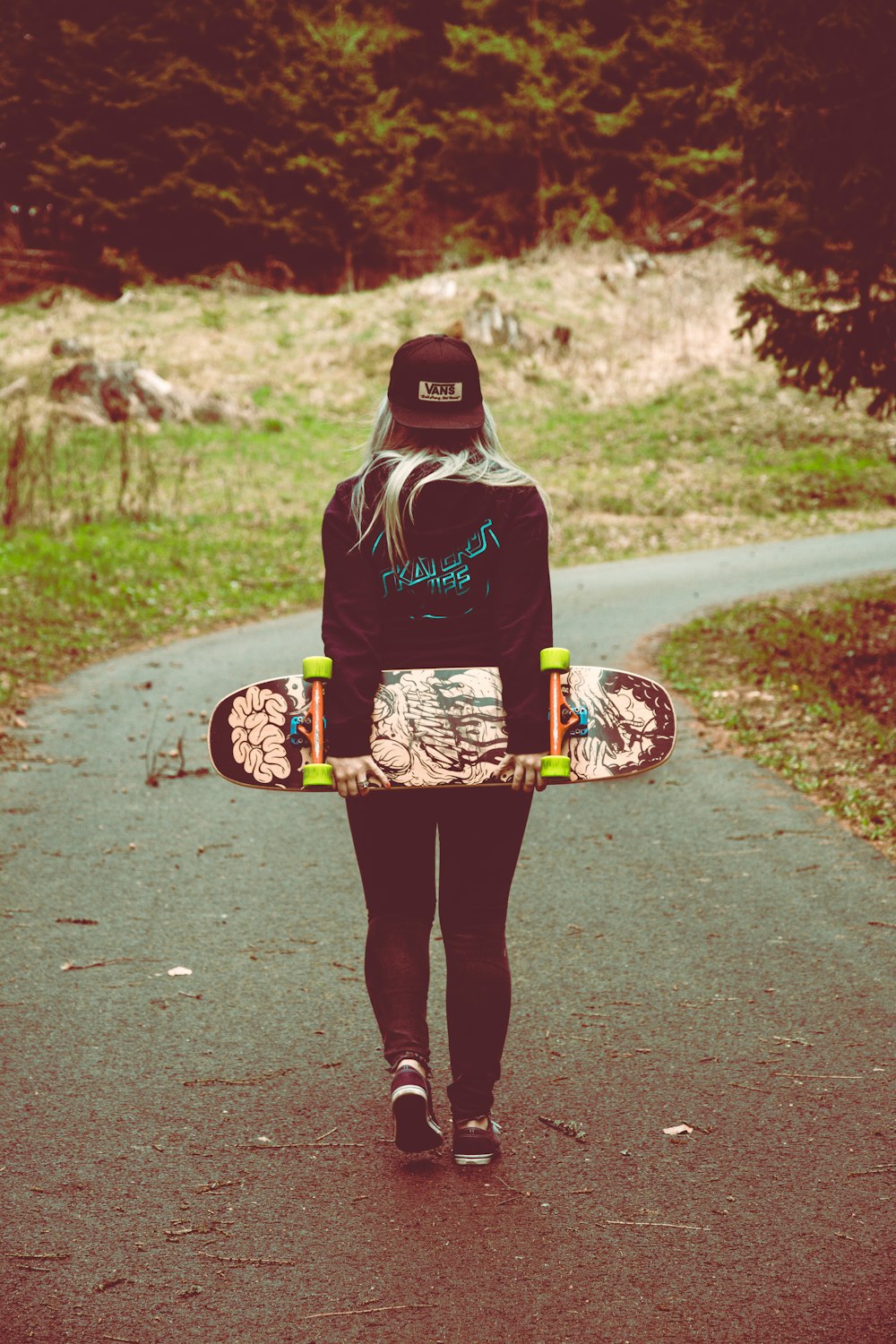 Donna che trasporta skateboard che cammina sul sentiero