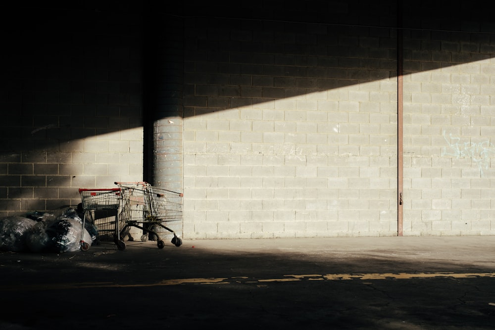 Un carrito de compras sentado junto a una pared de ladrillos