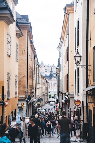 A charming street in Alba lined with restaurants and shops, bustling with visitors.