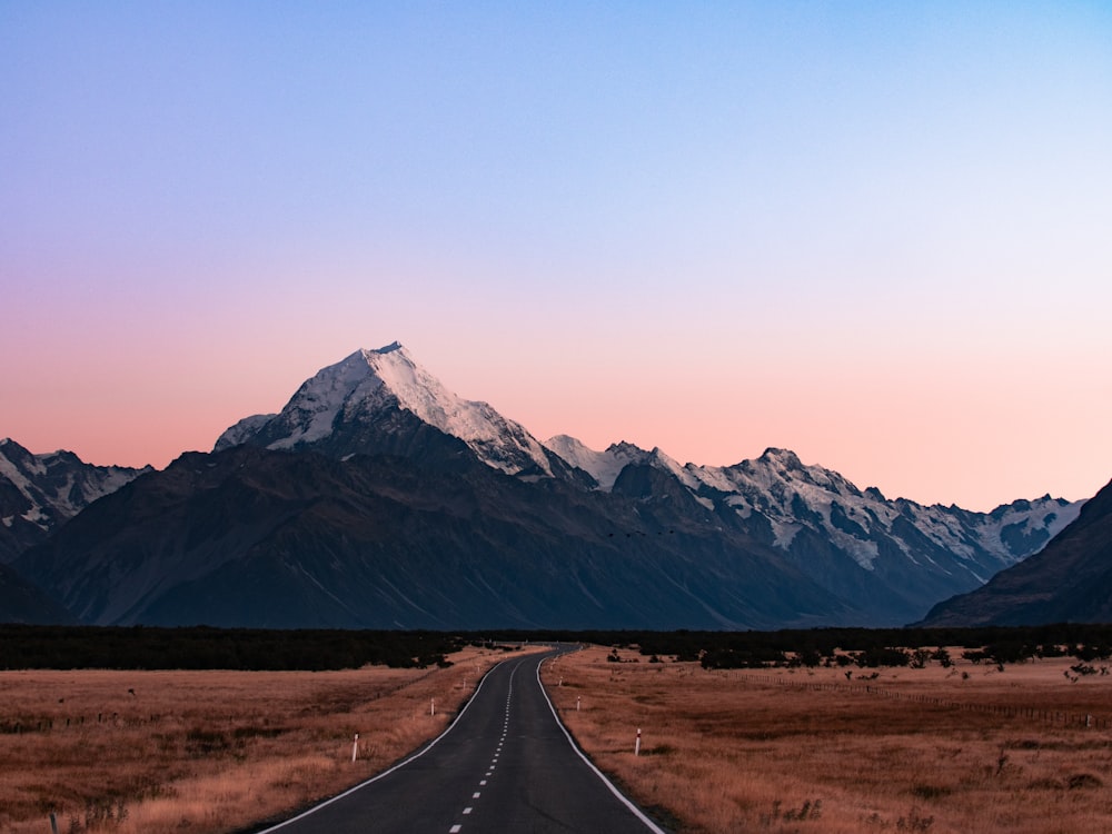 snow-capped mountains near concrete road