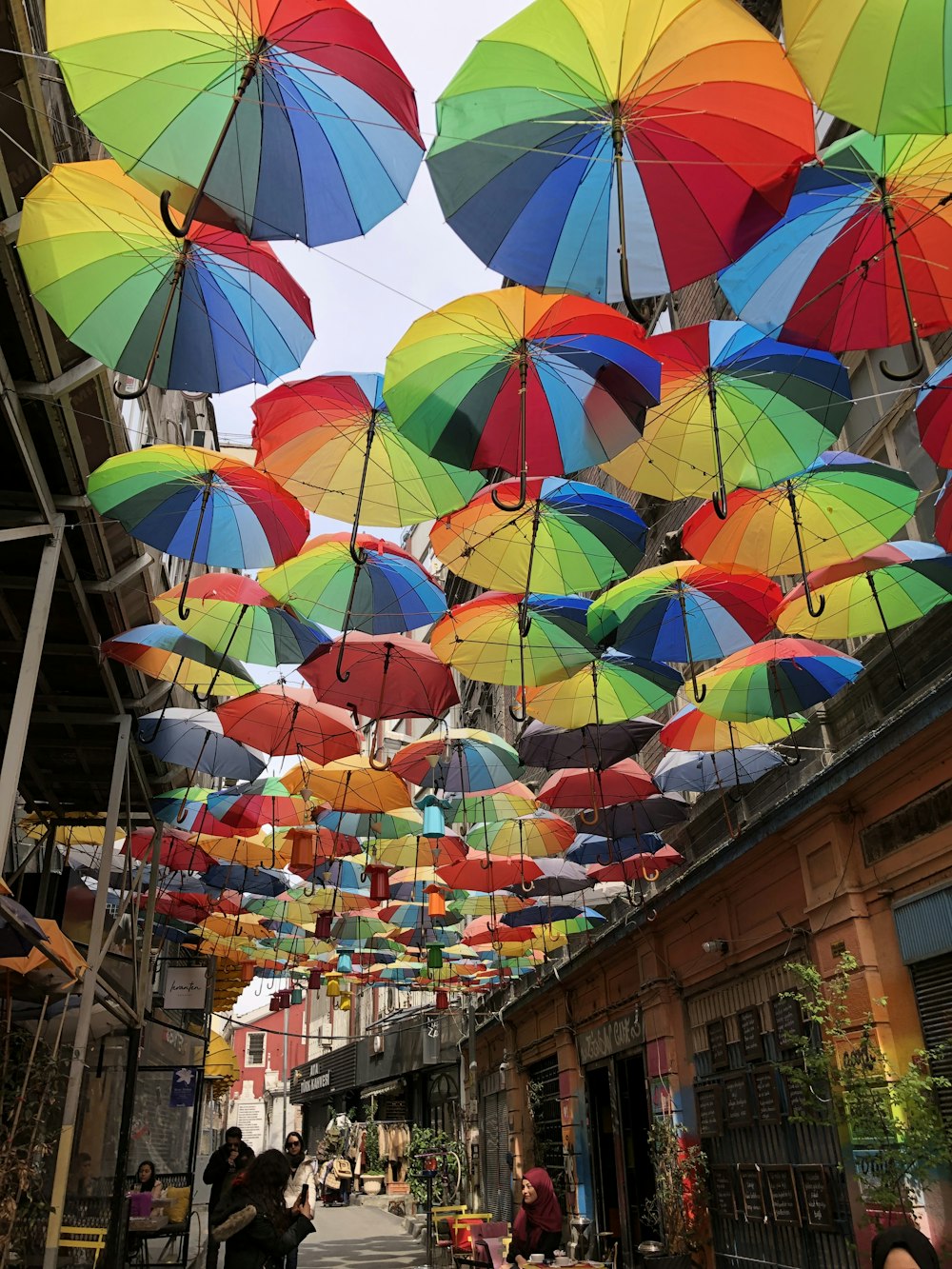 people walking under multicolored umbrellas between buildings