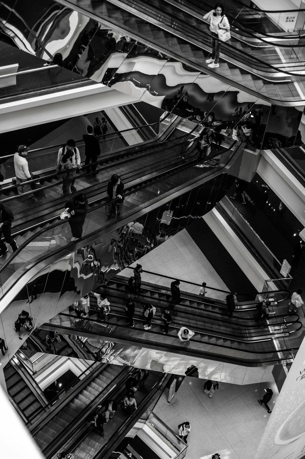 people riding escalators inside building in grayscale photography