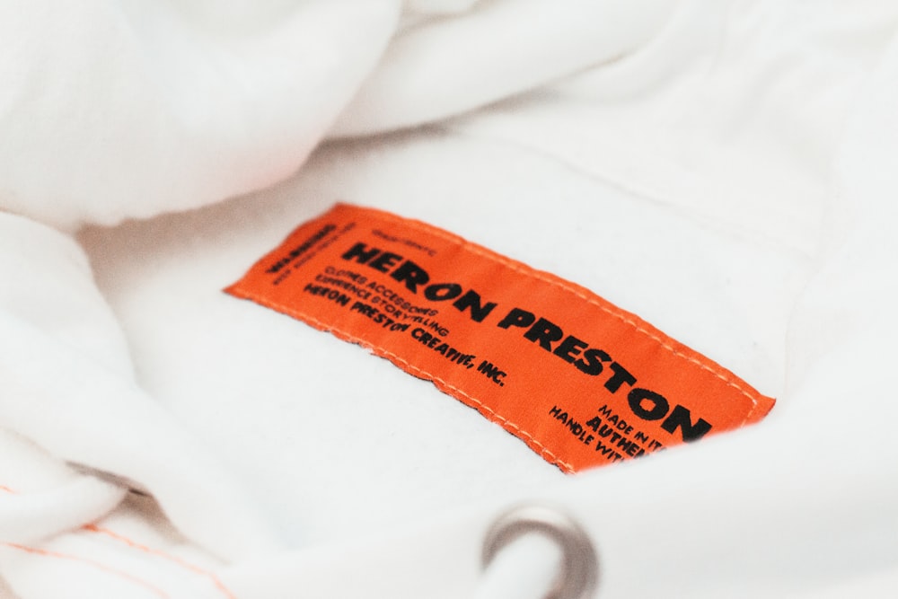 Uma etiqueta em uma camisa branca que diz Heron Preston