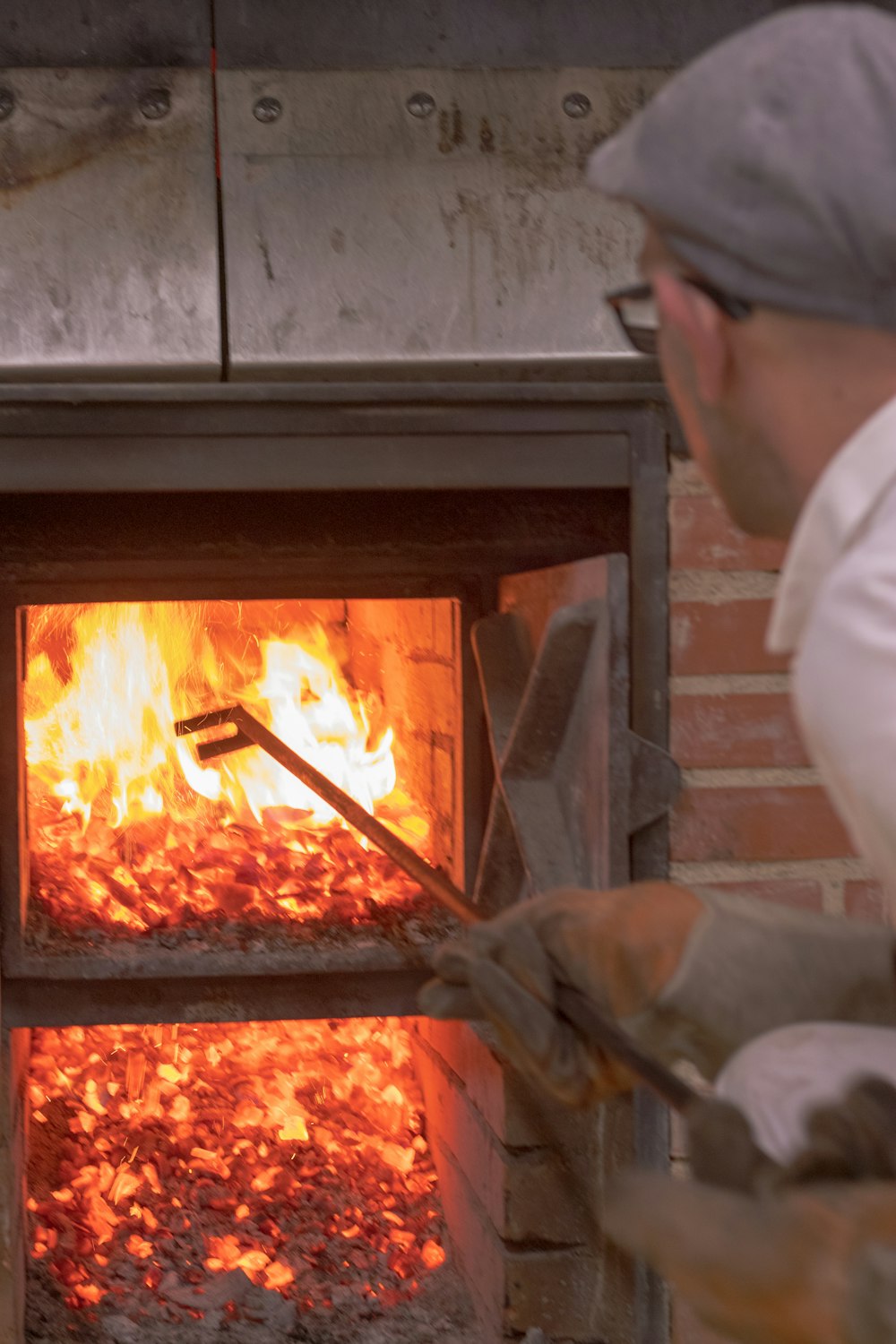 man picking with long rod on wood fired oven