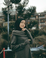 A playful winter outfit showcasing a chunky knit sweater, dark skinny jeans, and a deep burgundy hijab wrapped warmly.