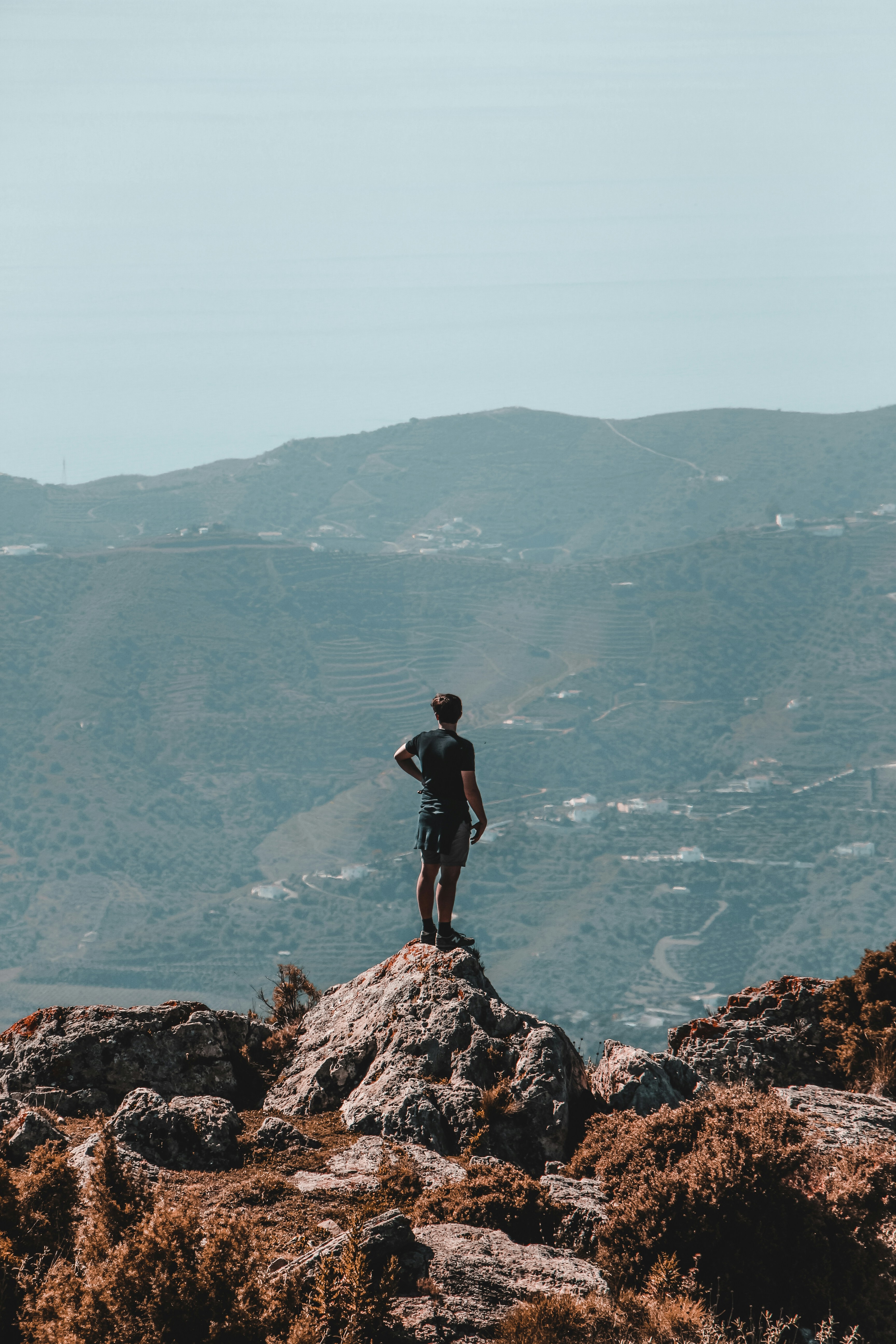Persona de pie en un acantilado con vistas a la montaña durante el día