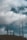 Multiple telecommunications towers rise against a backdrop of a cloudy sky. The towers are tall and metal, equipped with various antennas and satellite dishes. The scene suggests a rural or remote setting with a focus on the technology infrastructure.