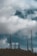 Multiple telecommunications towers rise against a backdrop of a cloudy sky. The towers are tall and metal, equipped with various antennas and satellite dishes. The scene suggests a rural or remote setting with a focus on the technology infrastructure.