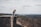 woman sitting on cliff's edge overlooking forest during daytime