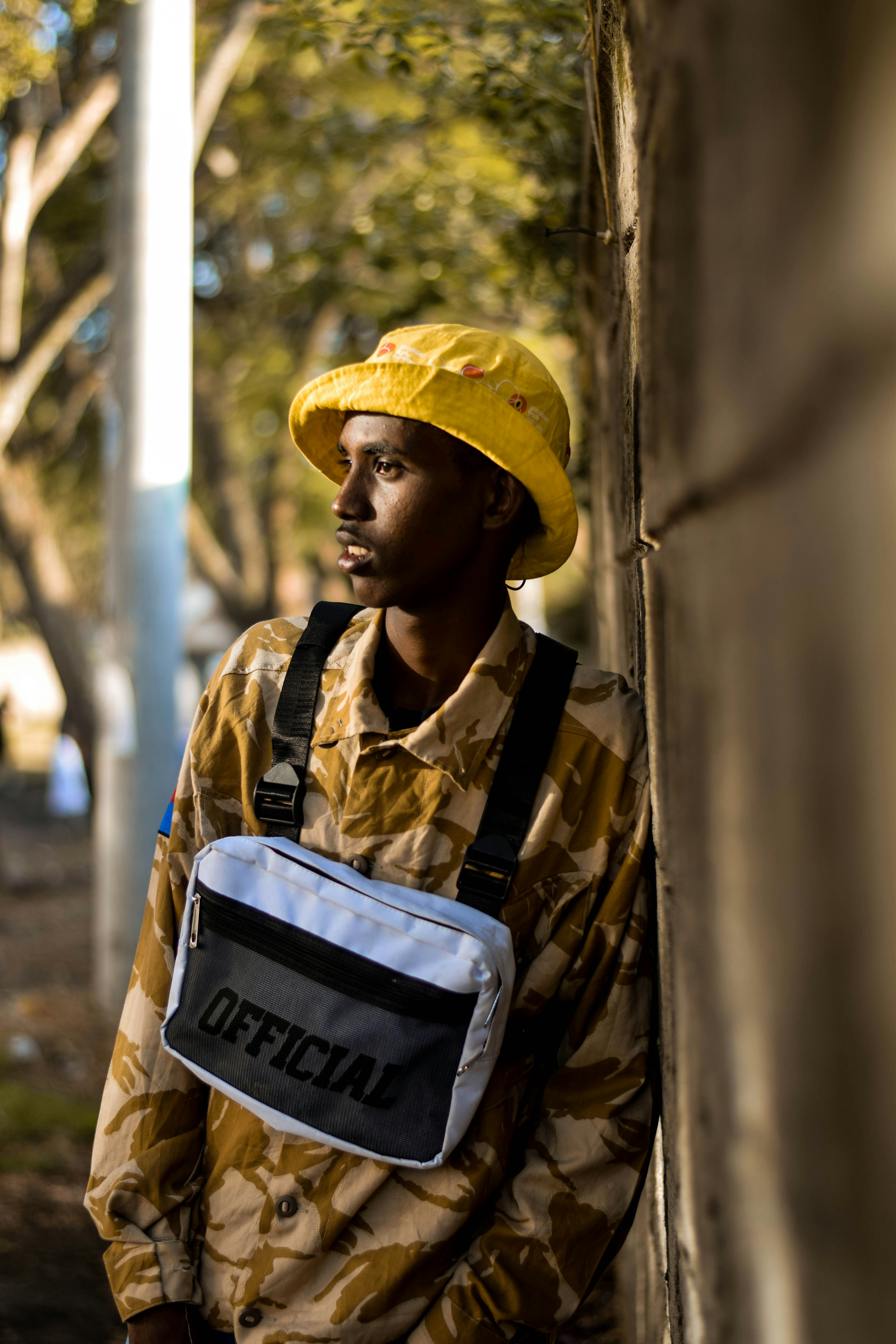 man in brown and beige floral dress shirt leaning on wall
