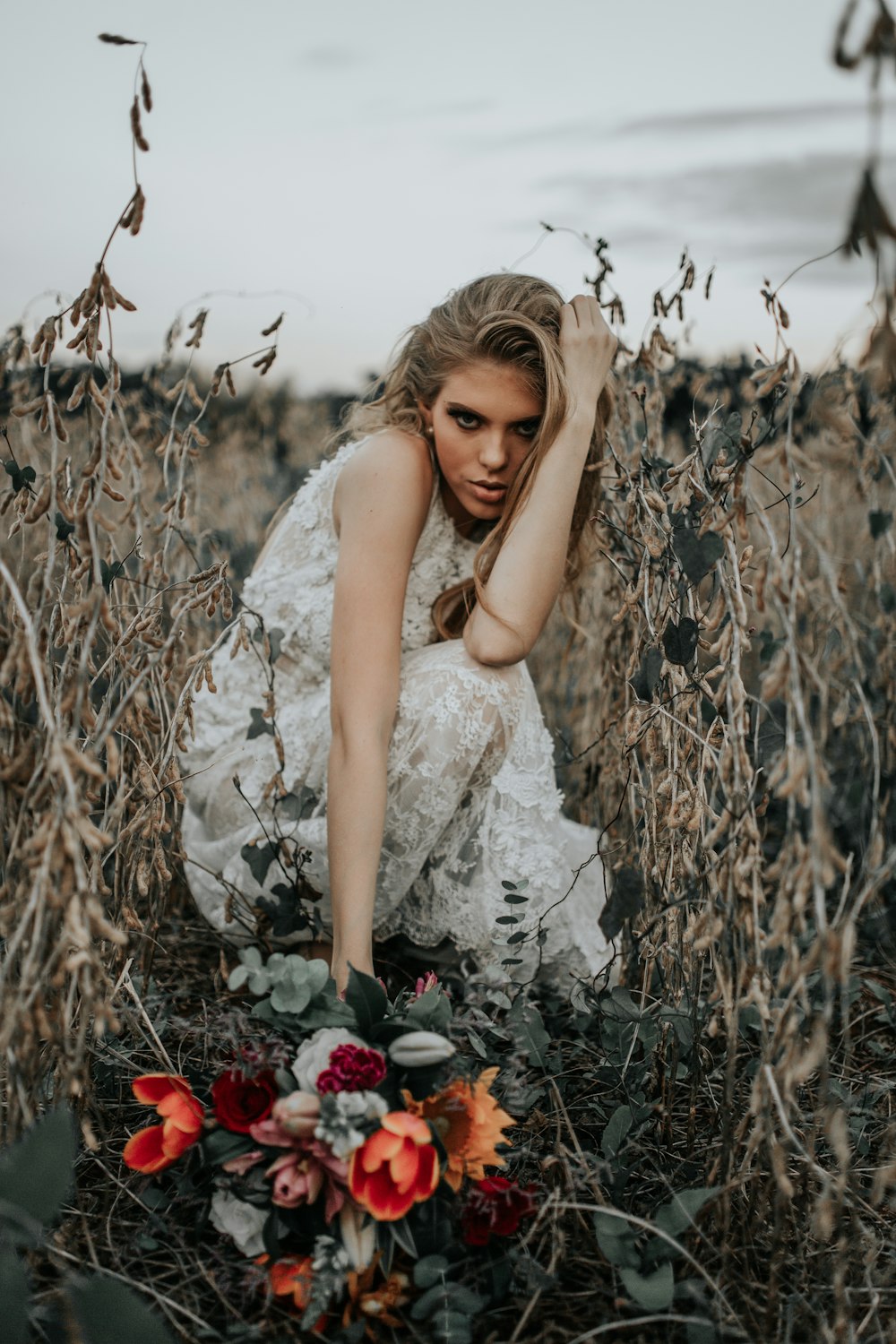 a woman kneeling in a field of tall grass