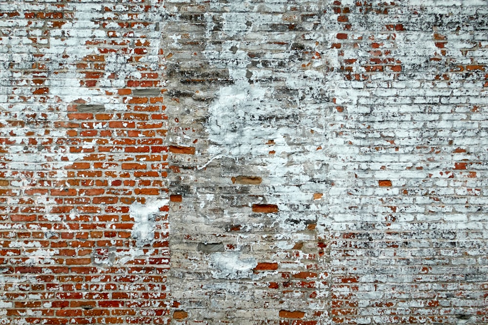 un vecchio muro di mattoni con vernice scrostata su di esso