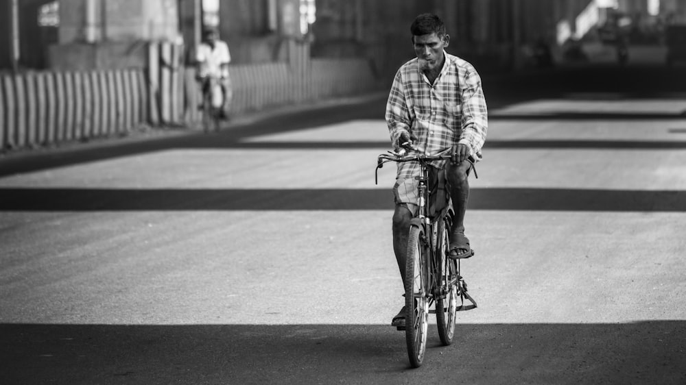 grayscale photography of man riding bicycle