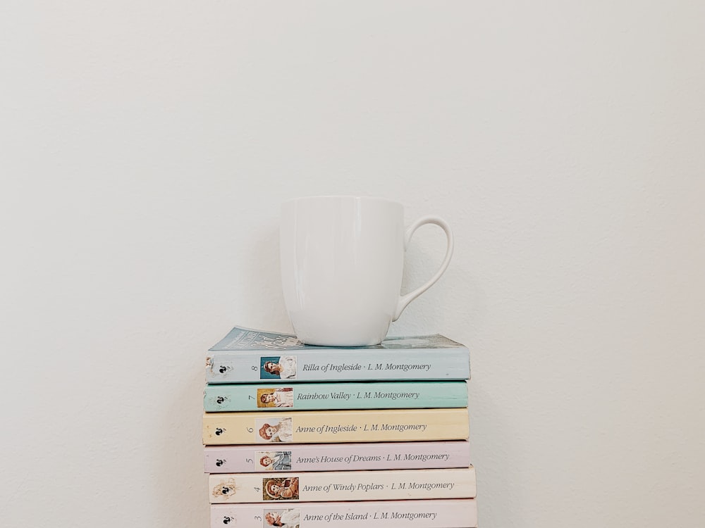white cup on top of piled books