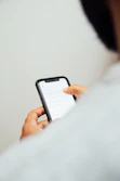 man in white top holding iPhone