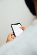 man in white top holding iPhone