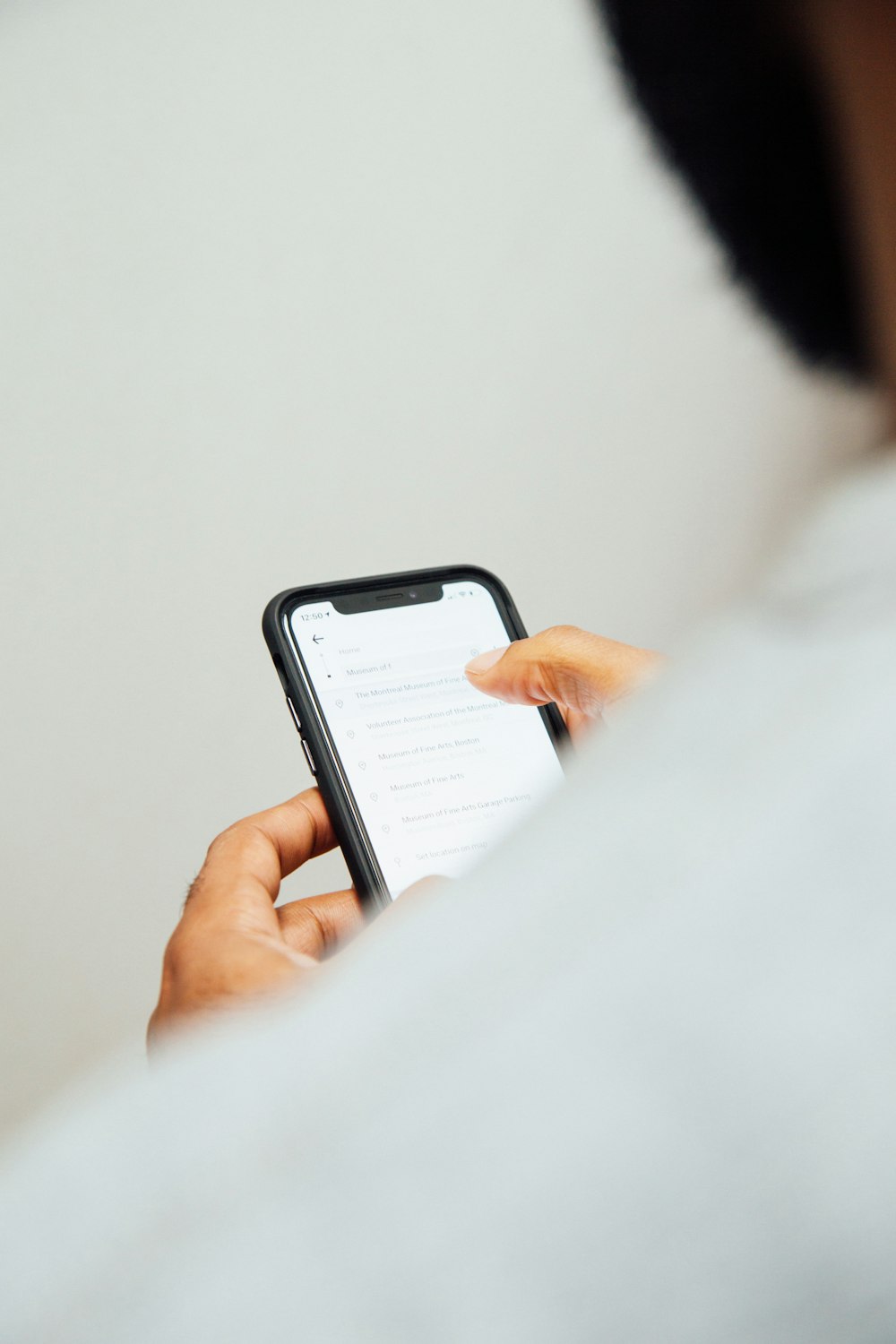 man in white top holding iPhone