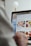 A person is using a laptop, navigating through the Uber Eats food delivery website. The screen displays various food items available for delivery in Montreal, QC, including options like McDonald's and Thai Express. The person appears to be browsing with their hand near the trackpad.