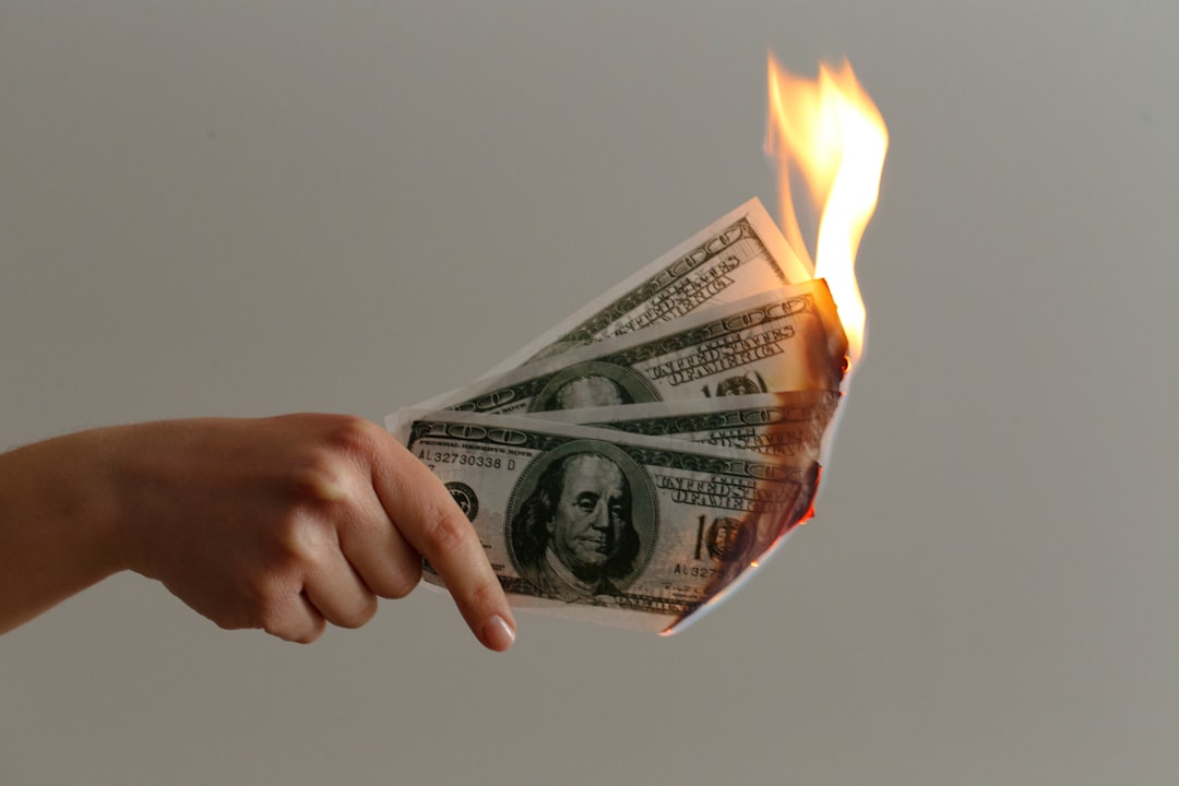Image of a hand holding four one-hundred dollar bills burning