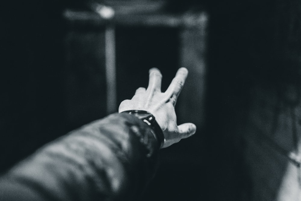 grayscale photography of person showing left hand