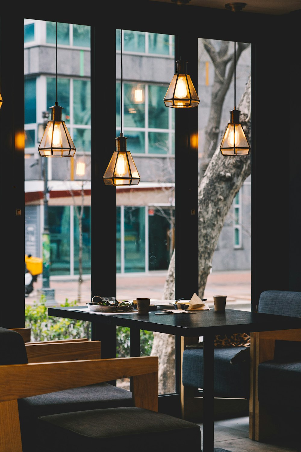 Table et chaise de salle à manger placées sous quatre suspensions éclairées