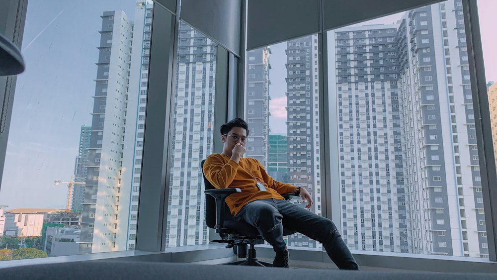 man sitting on chair near glass window