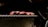 Slices of raw meat rest on a metallic grill with a black background, highlighting the texture and marbling of the meat.