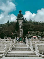 Scenic view of a pilgrimage site with pilgrims walking towards a large Marian statue.