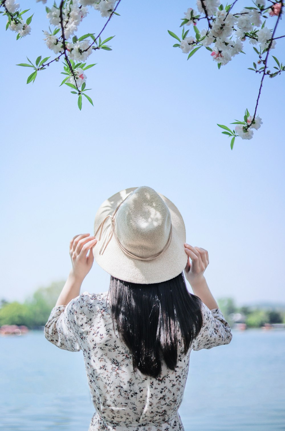 Mujer sosteniendo sombrero beige mientras mira hacia el mar