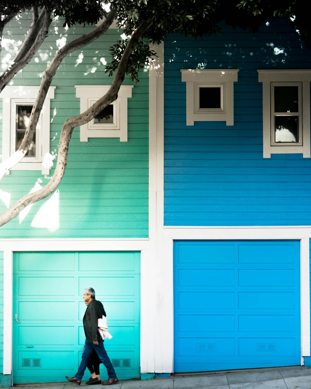 Hombre con chaqueta caminando al lado de la casa azul