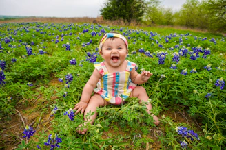 Smiling toddler wearing colorful baby clothes playing in a sunny garden