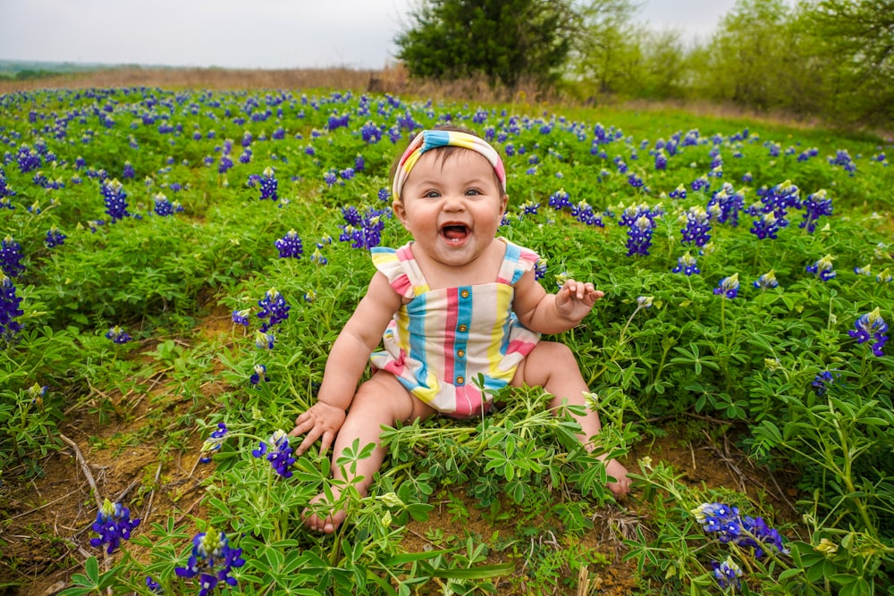 un bambino seduto in un campo di fiori blu