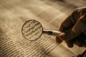 Careful hands inspecting delicate bible paper with archival cotton fibers
