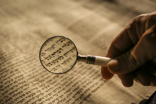 Close-up of a researcher carefully examining ancient texts under warm lighting.