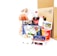 A collection of various grocery items displayed together. There is a loaf of bread in a bag, a plastic bottle of Coca-Cola, a carton of eggs, milk, yogurt containers, a packet of butter, and a plastic tray of vegetables. Behind these items, there is a cardboard box. The products feature labels in a non-English script.