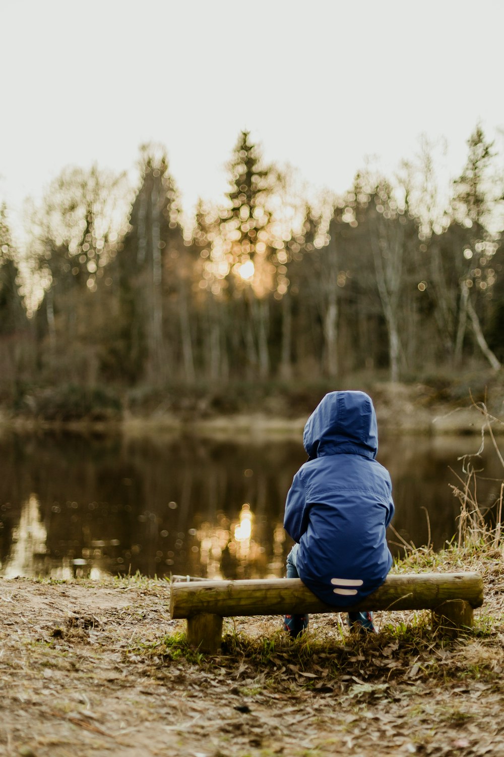 a person sitting on a bench near a lake