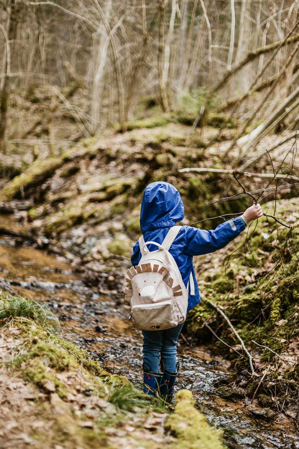 toddler in blue hoodie carrying backpack