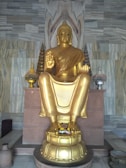 Close-up of a sleek golden sculpture on a black marble pedestal.