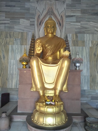 Close-up of a sleek golden sculpture on a black marble pedestal.
