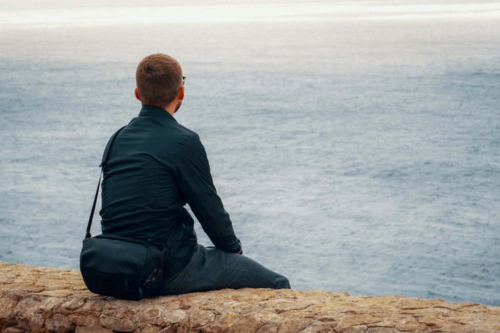 man sitting and facing the ocean